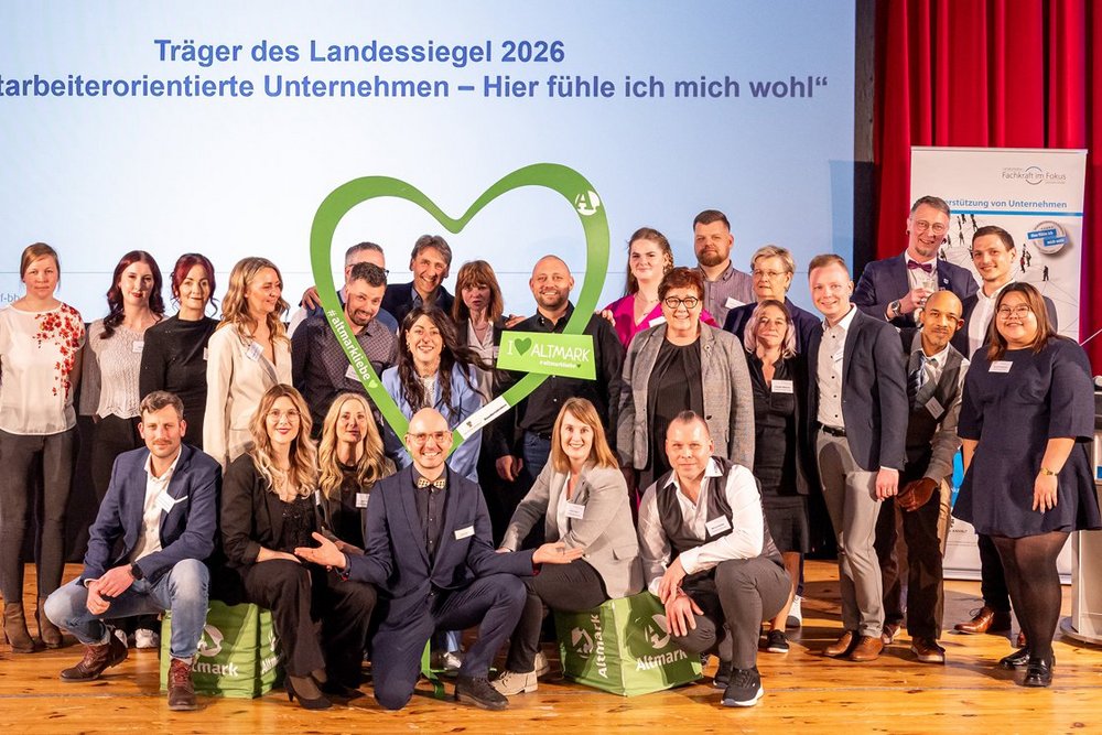 Viele Menschen stehen auf einer Bühne und jubeln, weil sie gerade eine Auszeichnung von der Arbeitsministerin des Landes Sachsen-Anhalt erhalten haben.