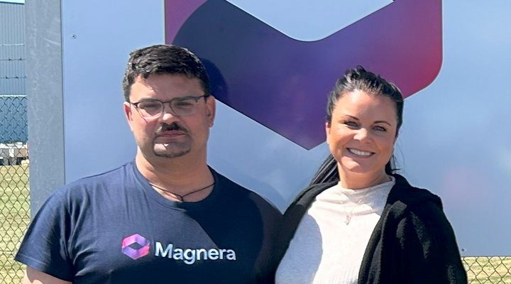 Dmytro Kumurzhy und Katherina Kumorowska, Personalleiterin der Magnera Aschersleben GmbH Ein Mann steht in Arbeitskleidung neben einer Frau vor einem Werbeschild
