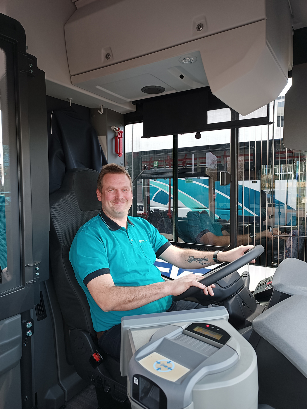 Ein Mann sitzt freudestrahlend am Steuer eines Busses